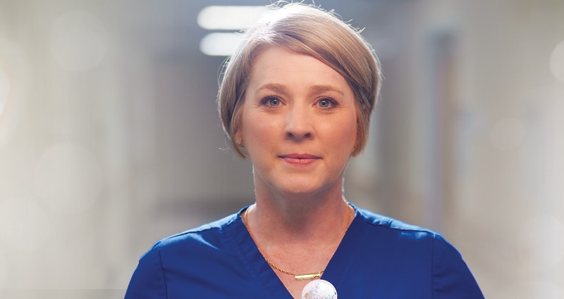 A woman with blonde hair wearing blue scrubs