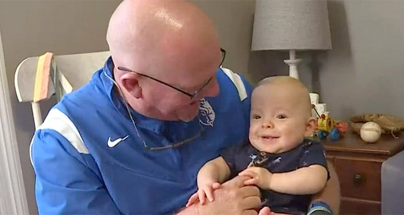 Adult holding smiling baby in rocking chair