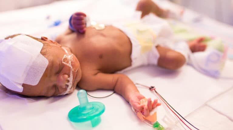 baby in NICU sleeping on back