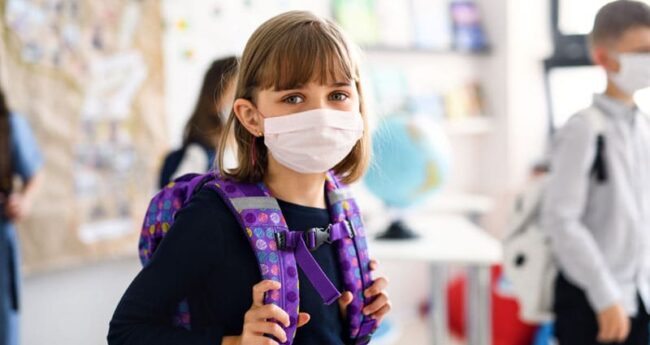child with backpack wearing face mask