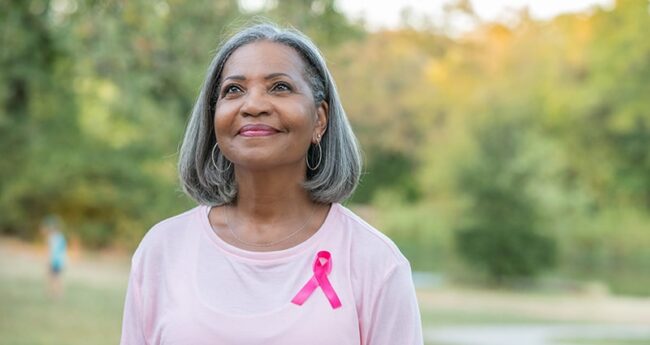 Cancer_2021-0924_LifeAfterBreastCancer woman smiling wearing pink ribbon
