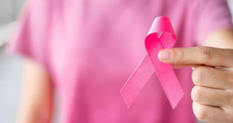 woman in pink shirt holding pink ribbon
