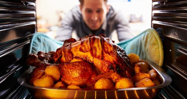 man taking roast turkey out of the oven