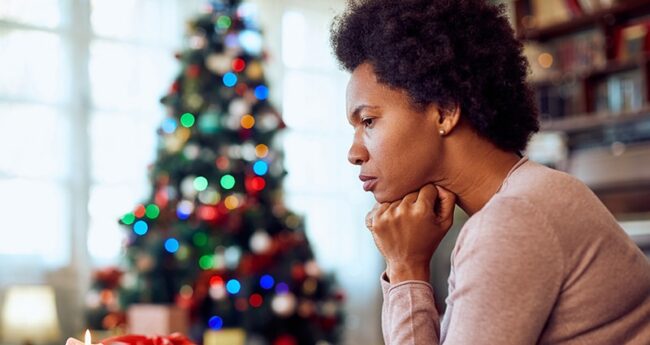sad young woman thinking in front of Christmas tree
