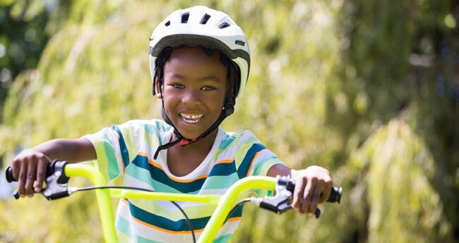 ChildrensHealth_2022-0222_ChildSafetyChecklist smiling kid riding bike wearing helmet