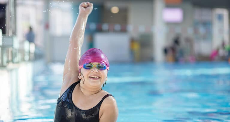girl in swimming pool with pink swim cap and goggles