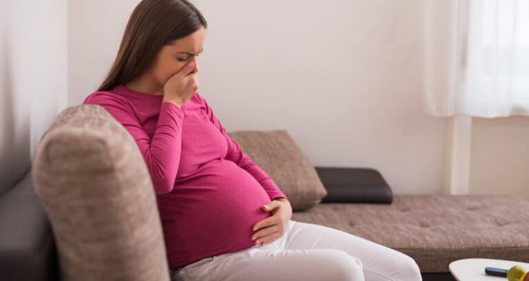 Pregnant woman holding mouth indicating nausea