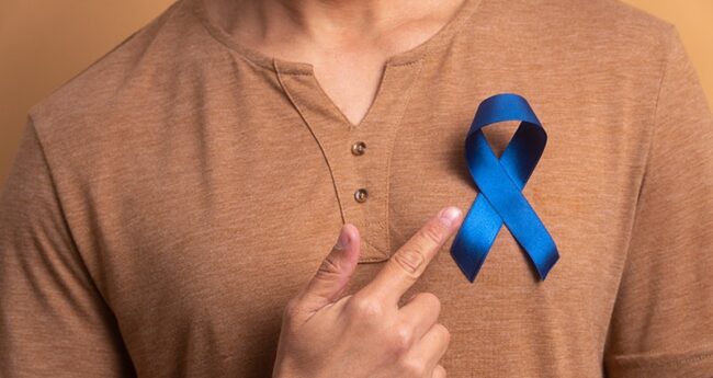 Cancer_2022-0301_ColonCancerQuiz woman pointing to blue ribbon
