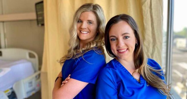 angels two nurses smiling and standing back to back