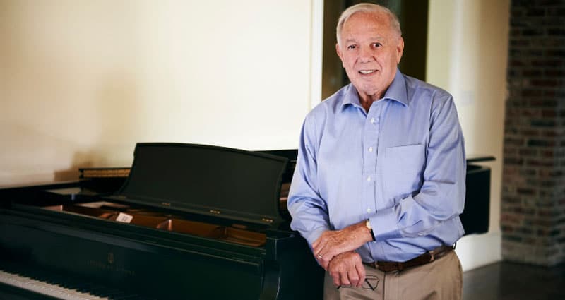 James Devin Moncus standing next to piano