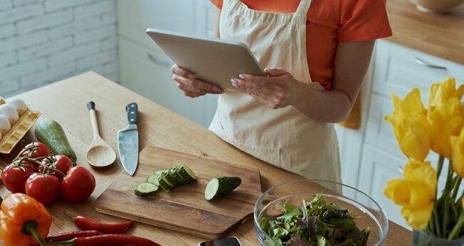 woman holding a tablet looking at recipe in kitchen