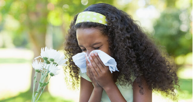 Young Girl sneezing outside