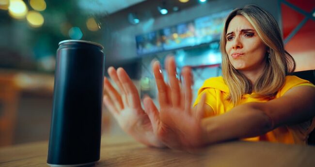woman holding hands out toward canned drink as if pushing it away