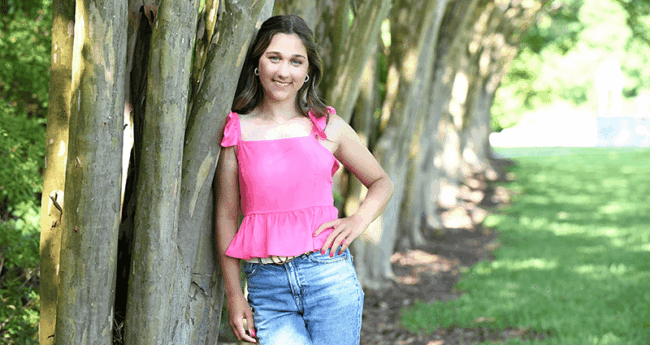Lauren-ForHeader Lauren, smiling teenager in pink shirt and jeans by a tree