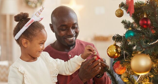 dad and daughter decorate Christmas tree