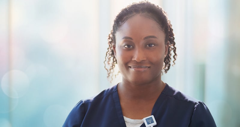 A smiling woman wearing blue scrubs