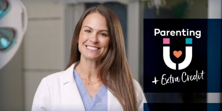 A woman wearing a white medical coat smiles at the camera.