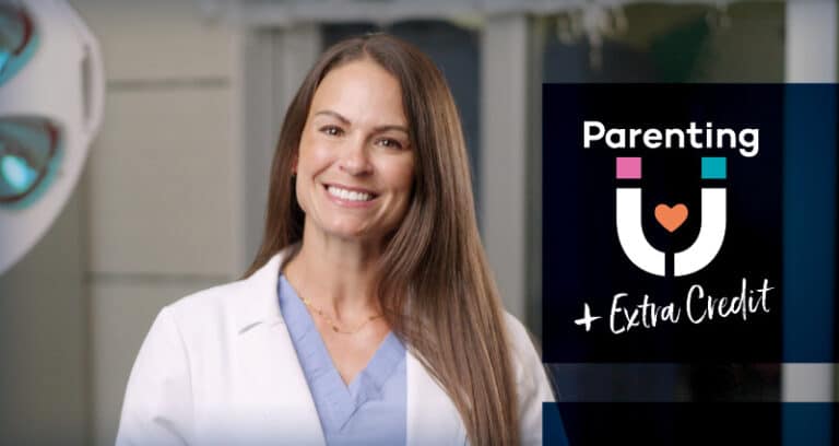 A woman wearing a white medical coat smiles at the camera.