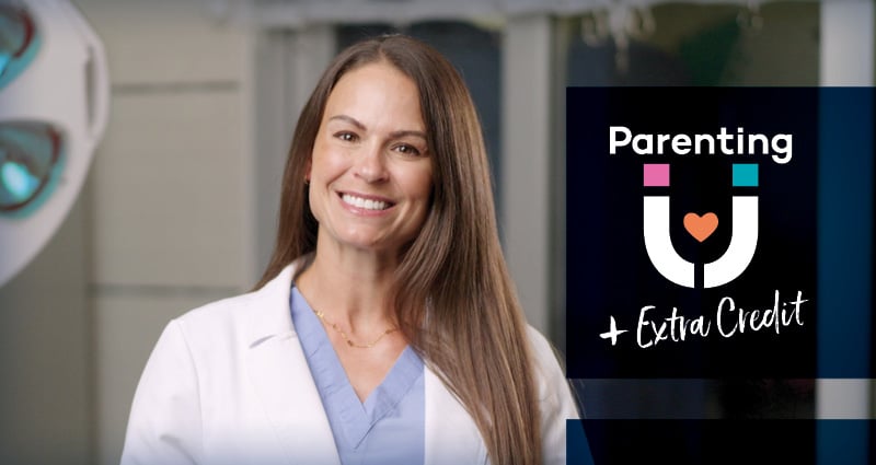 A woman wearing a white medical coat smiles at the camera.