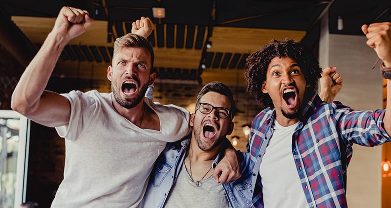 three friends excitedly cheering their team