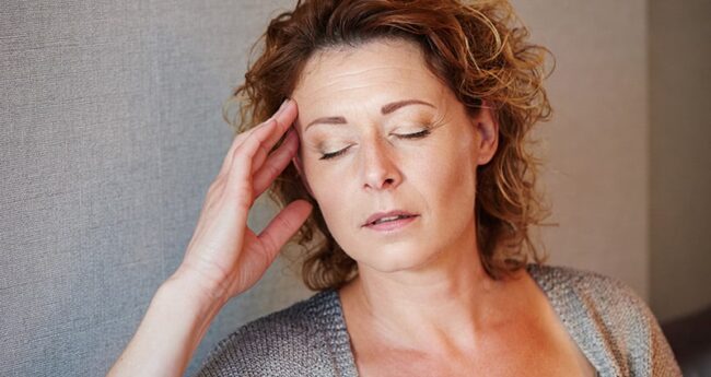 woman with hand by her temple and eyes closed