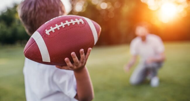 HeartHealth_20220217_WhatScoreWithArterialCalciumTests boy throwing football to kneeling dad in background
