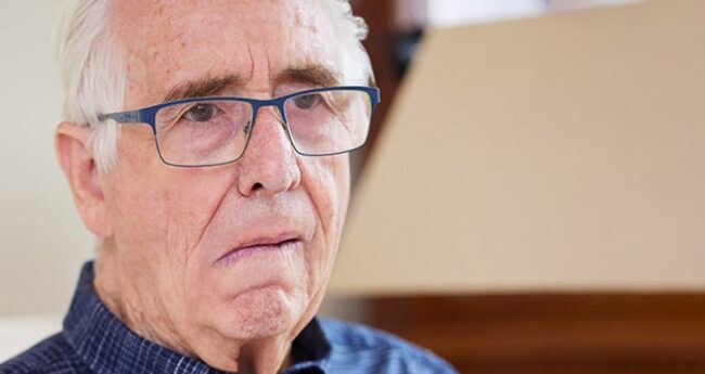 Portrait Of Senior Man At Home Suffering From Stroke Showing Dropped Side Of Face