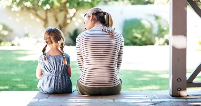 young girl and adult woman sitting on porch talking