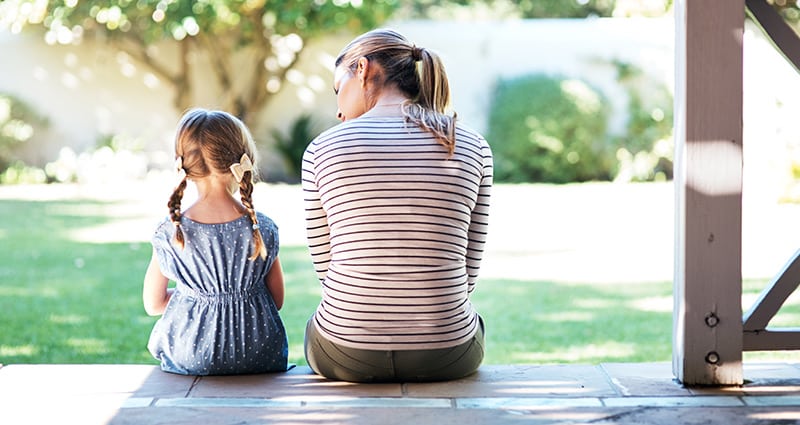 young girl and adult woman sitting on porch talking