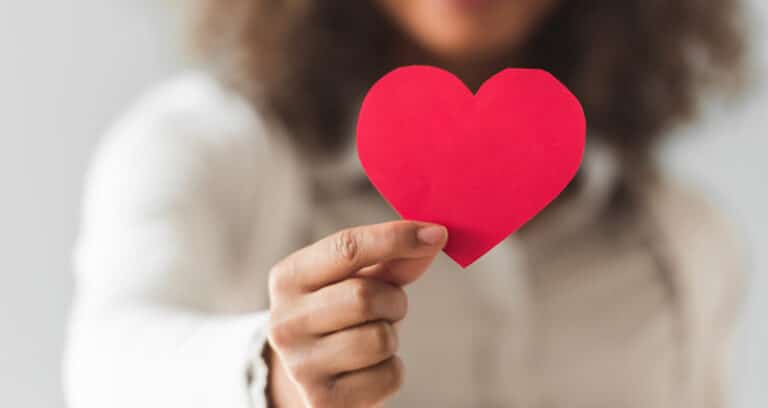 person holding red construction paper heart shape