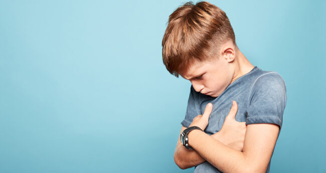 Tween boy covering his chest