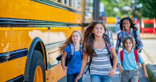 Kids Running By School Bus