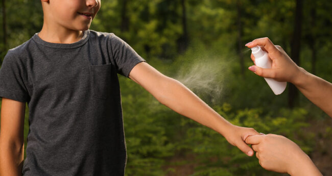Mom Spraying Child’s Arm with Bug Spray