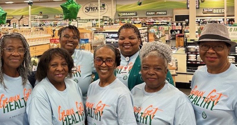 A group of women smile for a photo inside a grocery store