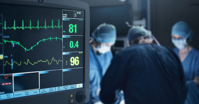 cabg blog A heart monitor is in the foreground while surgeons are performing surgery in the background