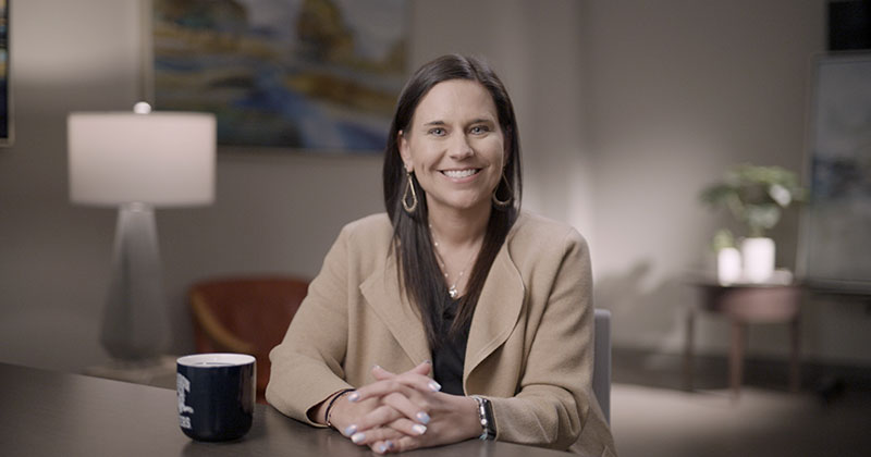 A woman sits and smiles at the camera