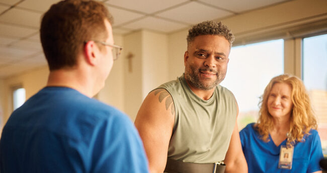 Man at rehab smiling with healthcare workers